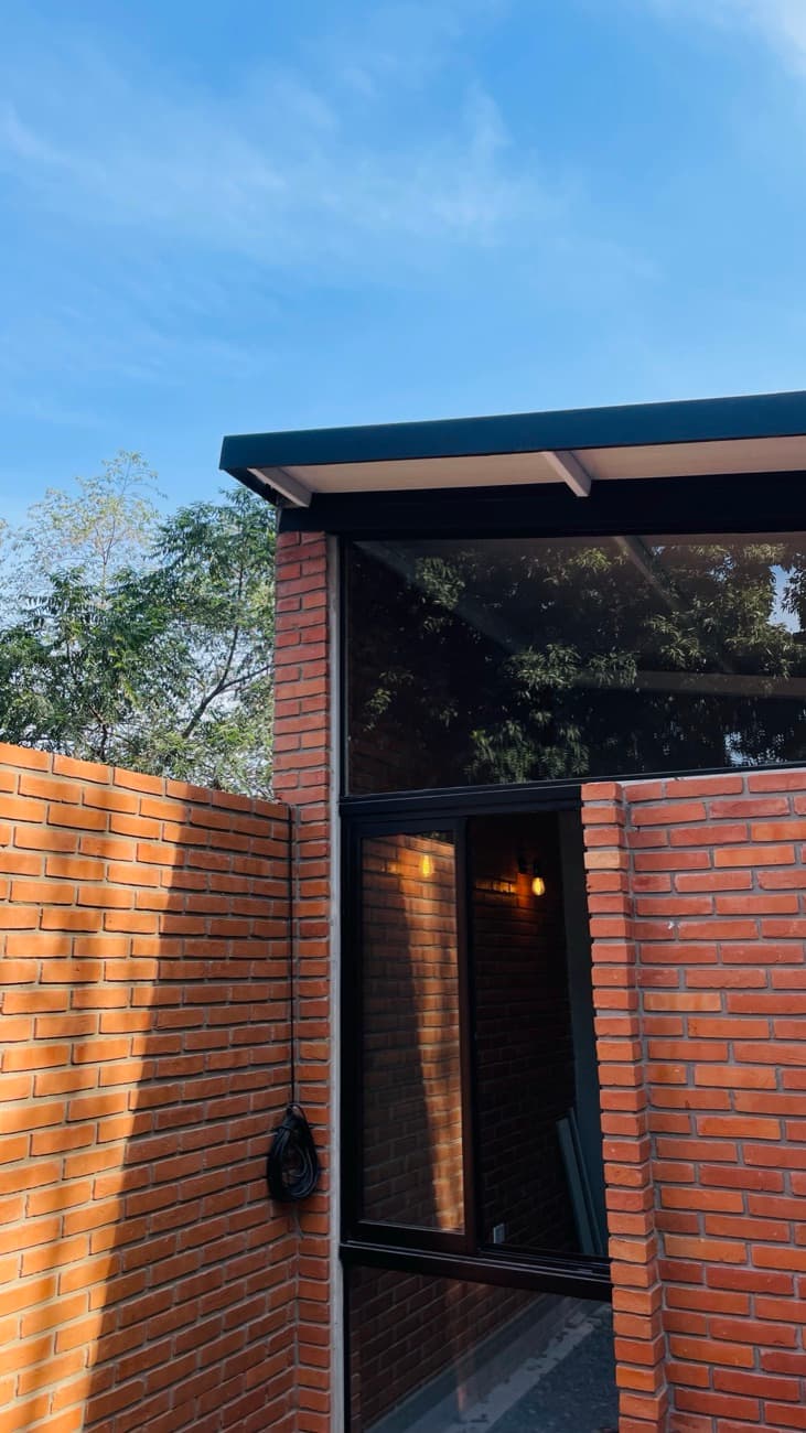 La esquina con el ventanal y las luces cálidas prendidas adentro, al atardecer