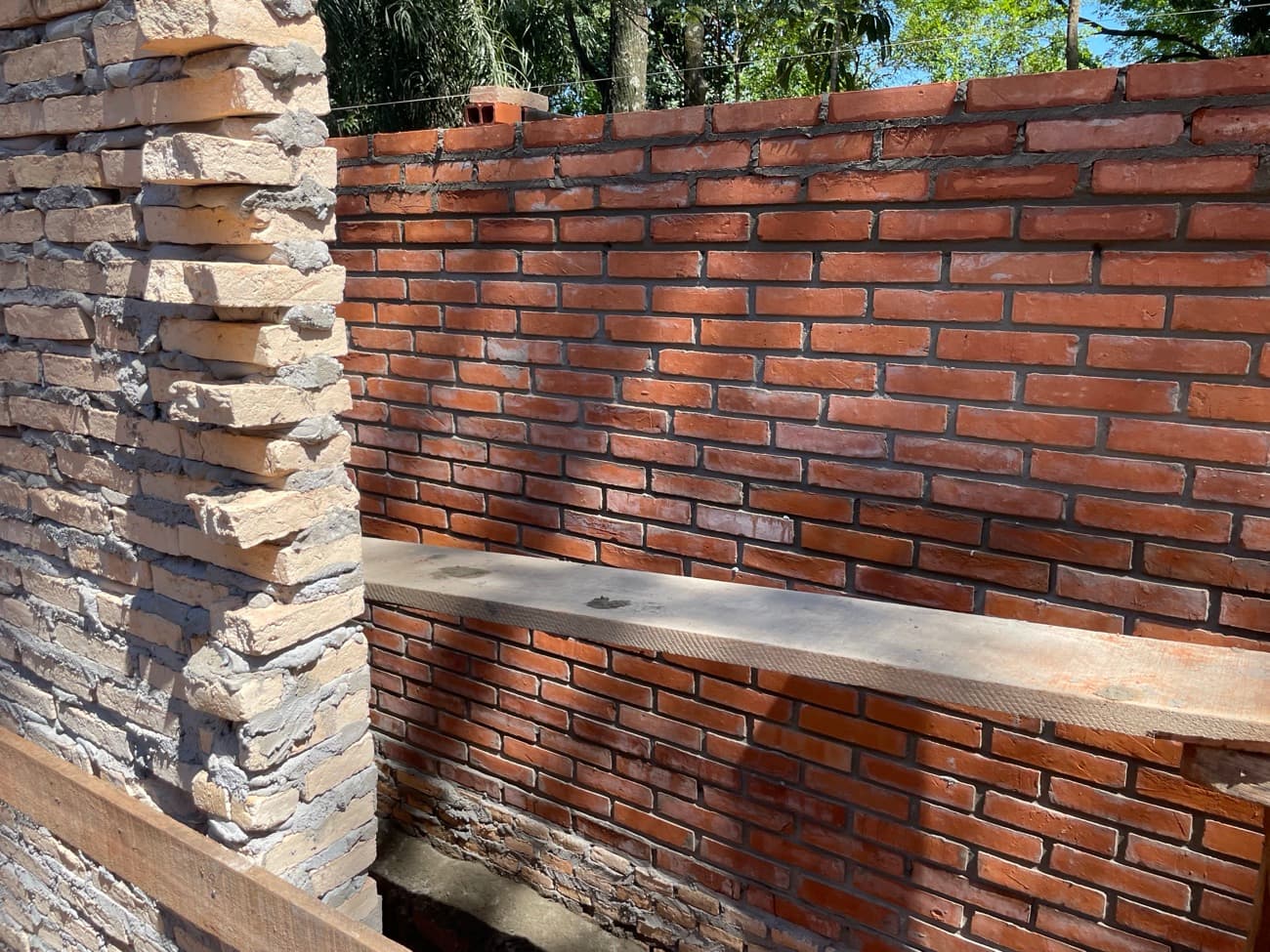La mesada de hormigón del quincho apoyada sobre el muro de ladrillo, junto al muro de piedra