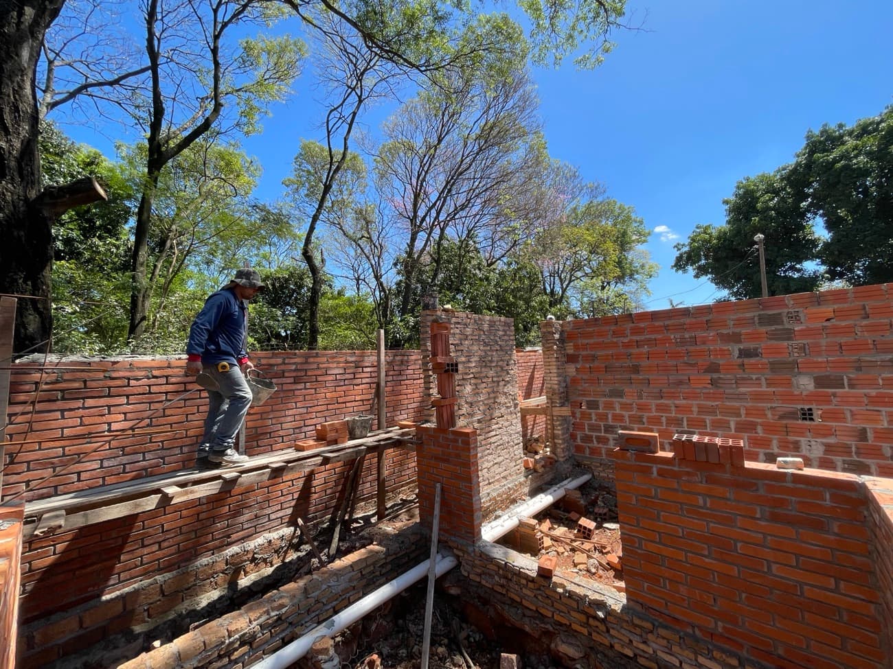 Un operario caminando sobre el andamio a la altura del muro, contra el cielo