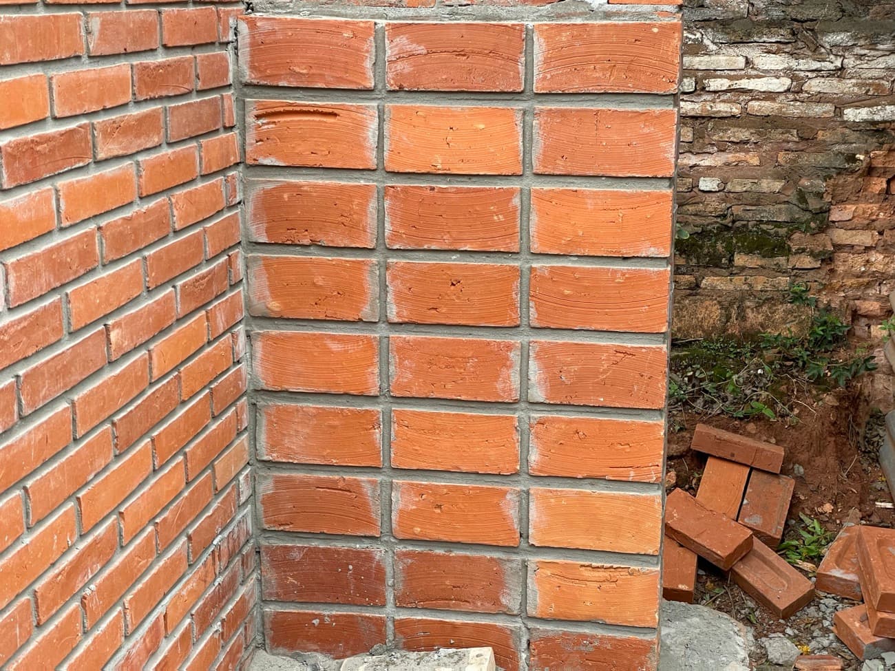 Detalle del encuentro de dos paños de ladrillo con la junta tomada, gris y pareja